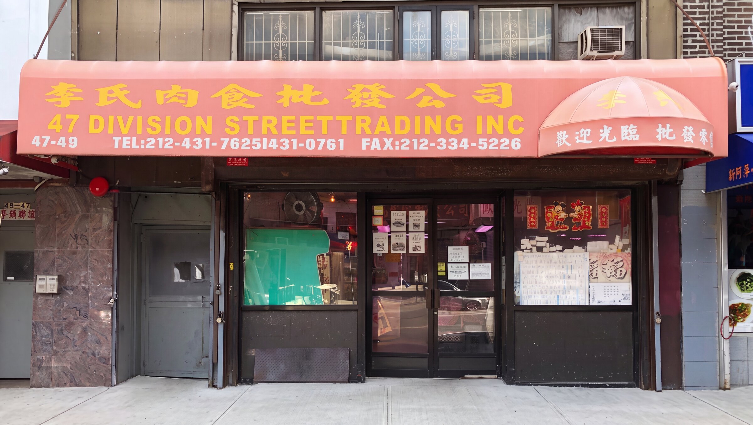 The 47 Division Street Trading storefront, its pink awning reading 李氏肉食批發公司, with a forklift and pallets outside